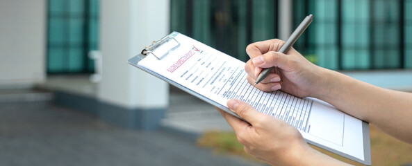 Foreman's hand is using a pen checking on building inspection report form to QC building quality of...