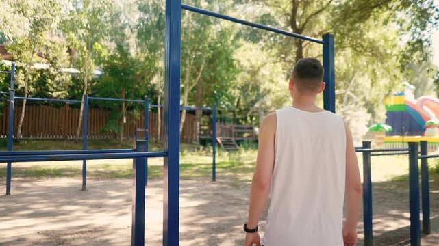 Handsome pumped up young male bodybuilder doing exercises on horizontal bar and parallel bars outdoors on the street. Beautiful male body shapes, beauty and health, training and motivation