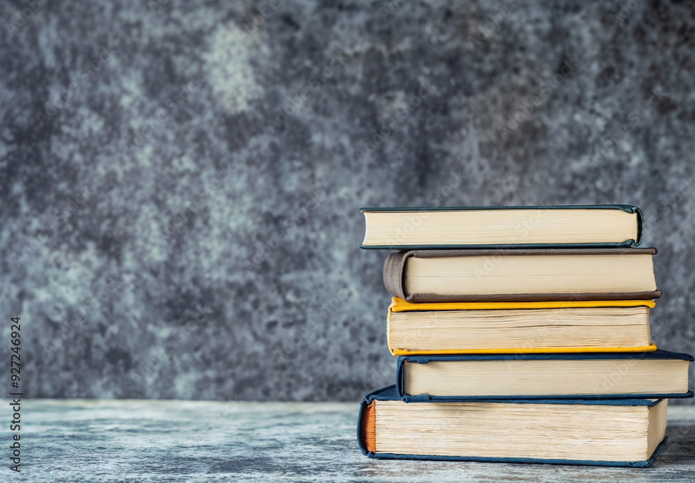 Aufkleber stack of books is sitting on a table, with copy space on grey wall textured background