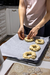 Baker put round dough for bagels in tray. Homemade preparation on bagel dough in kitchen. 