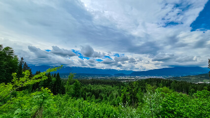 Panoramic aerial view of the city of Villach surrounded by majestic mountain ranges of Julian Alps and Karawanks, Carinthia, Austria, Europe. Idyllic forest walk near the Landskron Castle. Cityscape.