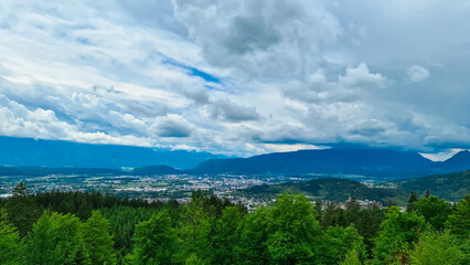 Panoramic aerial view of the city of Villach surrounded by majestic mountain ranges of Julian Alps and Karawanks, Carinthia, Austria, Europe. Idyllic forest walk near the Landskron Castle. Cityscape.