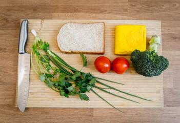 Cutting board with ingredients for preparing tofu scramble with vegetables.
