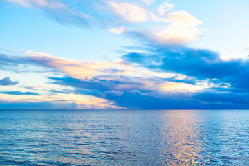 Obraz premium Serene ocean view at sunset, with vibrant colors reflecting off the water and clouds scattered across the sky. Picturesque twilight over the ocean