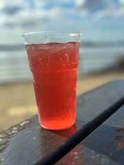 A plastic cup of fruit cider outside a pub on a summer afternoon. The River Mersey can be seen in the background