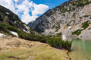 Panoramic view of serene alpine lake Hölltalsee (Silberkarsee) surrounded by majestic mountain ridges in Schladming, Styria, Austria. Hiking trail in Austrian Alps in spring. Schladminger Tauern