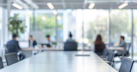 Minimalist plant on conference table in modern office. A single plant sits on a white conference table in a modern office. The background shows a blurred view of coworkers at their desks.