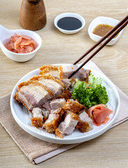 Crispy pork belly in a white plate on a wooden table