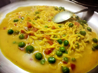 Maggie Noodles with Green peas served in a bowl over a rustic wooden background