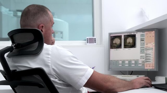 In a high-tech control room, a radiologist reviews brain scan results on monitors while a patient undergoes an MRI or CT scan. Ideal for showcasing advanced medical diagnostics and equipment.