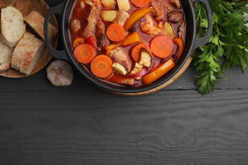 Tasty homemade stew with vegetables and bread on grey wooden table, flat lay. Space for text