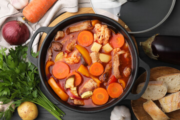 Tasty homemade stew with vegetables and bread on grey wooden table, flat lay