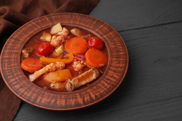 Tasty homemade stew with vegetables on grey wooden table, closeup. Space for text
