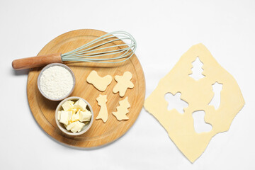 Raw dough, cookies, whisk and ingredients on white background, flat lay