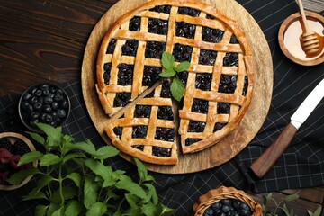 Tasty homemade pie with blueberries, fresh berries, mint, honey and knife on wooden table, flat lay