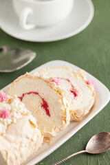 Homemade Meringue Cake Sweets Roll with Raspberry jam on ceramic plate.