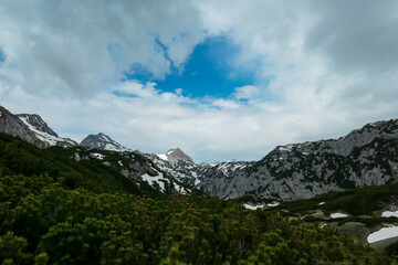 Fototapeta premium Scenic aerial view of majestic alpine landscape with snow-capped mountain ridges of Schladminger Tauern in Ramsau am Dachstein, Styria, Austria. Hiking trail through alpine greenery in Austrian Alps