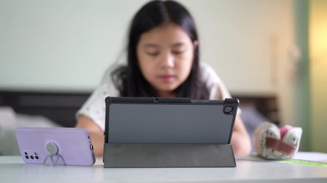 closeup smartphone and tablet with blur asian child reading speaking or kid girl talking and study online class or learn from home school by computer and mobile phone or people studying learning