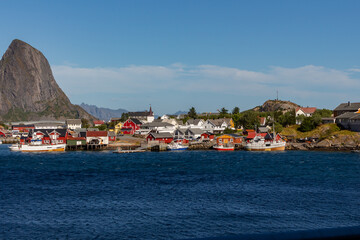 Set of white and red houses on coast with dark sea and mountain in the background