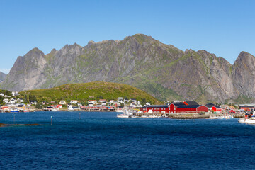 Set of red houses on the coast with green mountains in the background
