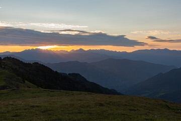 Sunrise with sun rays between the clouds and mountain ranges around