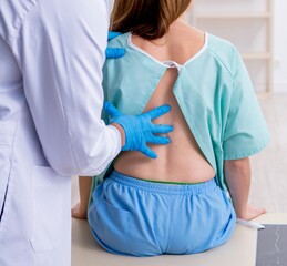 Young back injured woman visiting male doctor chiropractor
