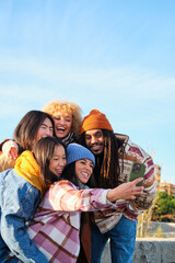 Young and diverse group of friends taking a selfie with a smartphone while on a street sidewalk in the city.