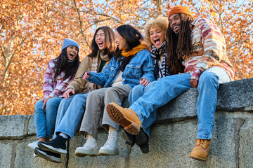 Happy playful multiethnic group of young friends bonding outdoors. Multiracial millennials students meeting in the city, concepts of youth, people lifestyle, diversity, teenage and urban life.