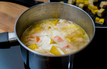 Chef at the kitchen preparing pumpkin porridge with tofu and vegetables
