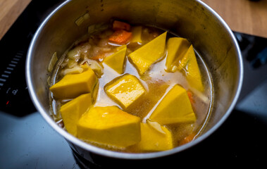 Chef at the kitchen preparing pumpkin porridge with tofu and vegetables