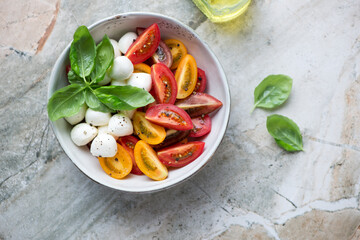 Bowl with italian caprese salad on a grey granite background, horizontal shot, view from above