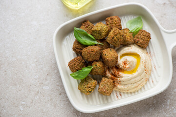 Serving tray with hummus and falafel on a beige stone background, horizontal shot, elevated view