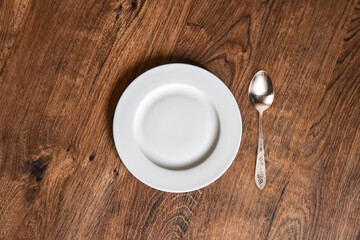 Ceramic white flat plate with spoon on wooden table