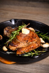 Pork cutlet on the bone in a piece of butter with garlic and rosemary in a frying pan 