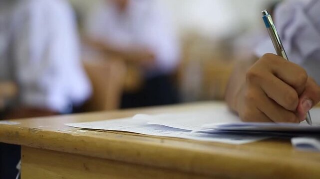 Assessment examination of high school students dressed in uniform.The students were doing the exams inside the classroom with stress.Slow motion
