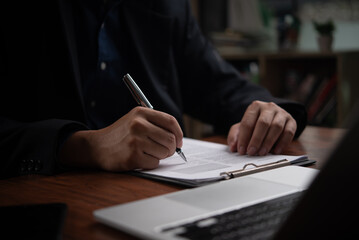 Close-up of a businessperson signing a contract with a pen, evoking professionalism and commitment.