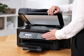 Woman using modern printer at workplace indoors, closeup