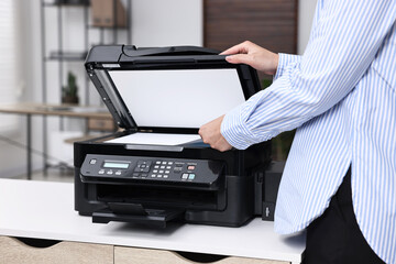 Woman using modern printer at workplace indoors, closeup