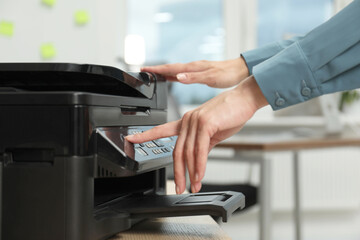 Woman using modern printer at workplace indoors, closeup
