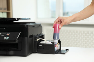 Woman refilling ink in modern printer at workplace indoors, closeup
