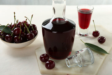 Delicious cherry liqueur and berries on white table