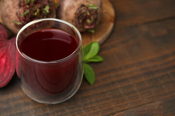 Fresh beet juice in glass, ripe vegetables and mint on wooden table, closeup. Space for text