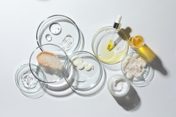 Petri dishes with different cosmetic products on white background, flat lay