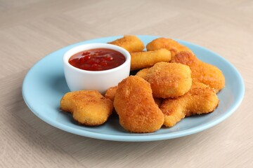 Tasty chicken nuggets with chili sauce on wooden table