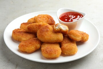 Tasty chicken nuggets with chili sauce on grey textured table