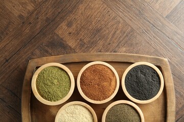 Different superfood powders in bowls on wooden table, top view