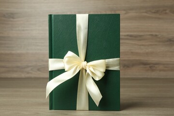 Book with ribbon as gift on wooden table