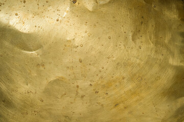 Gold-colored brass surface. Top left natural light. Scratches and stains. Copy space. Design background.