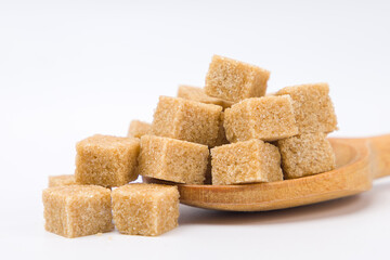 Cubes of brown sugar in a wooden spoon.