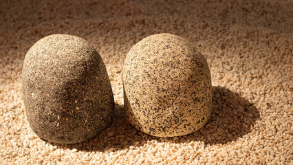 Two grey granite stones on small white gravel in a minimalist Japanese garden.